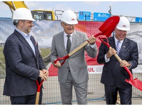 Federal Transport Minister Marc Garneau is seen standing between Montreal executive committee chairperson Benoît Dorais, left, and Philippe Rainville, president and director-general of ADM Aéroports de Montreal,  at ground-breaking ceremony for construction of the REM station at Trudeau airport in Dorval on July 19, 2019.