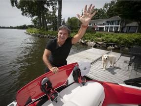 With his dog Oslo on the dock, homeowner Jacques Duval waves to a local sailor from his dock in Beaconsfield on Monday, July 22, 2019. Duval is one of more than 100 Beaconsfield residents who inexplicably find their properties on a map that shows they are at risk of flooding.