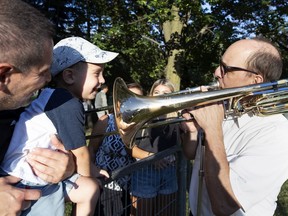 Orchestre symphonique de Montréal trombonist Pierre Beaudry plays for 3-year-old Matteao Russo before a performance in Wilfrid-Bastien Park on Tuesday.