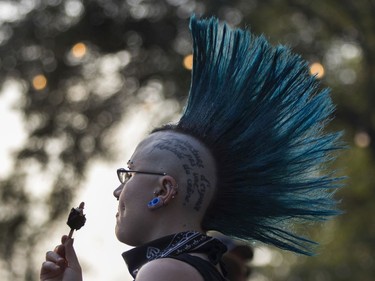 A woman eats an ice cream bar as  the band Cro-Mags perform at the '77 Montréal punk festival at Parc Jean-Drapeau in Montreal on Friday, July 26, 2019.