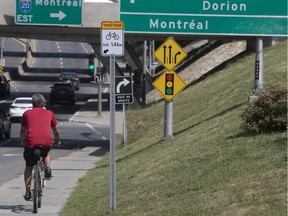 A cyclist uses the sidewalk as he make his way north on St-Charles Blvd. on Saturday near the Highway 20 overpass in Beaconsfield.