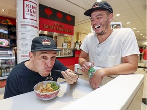 Co-owner Alex Winnicki, right, laughs as manager Fred Vaillancourt slurps some noodles at Kim Jen Ming, aka Cantine Satay Brothers inside the Royal Victoria Hospital on the MUHC's Glen Campus.
