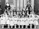 The confirmation class of 1953 poses in front of St. Alphonsus School with Father Baldwin and Sister St. Joseph of the Congregation of Notre Dame. Linda Frainetti is at the far right in the second row.