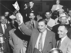 Premier Maurice Duplessis waves a Quebec flag to celebrate his election victory on July 16, 1952. Behind him holding a microphone is then-journalist, later premier, René Lévesque.