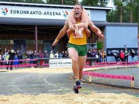 Vytautas Kirkliauskas of Lithuania carries his wife Neringa Kirkliauskiene as they compete during the Wife Carrying World Championships in Sonkajarvi, Finland, July 6, 2019. Lehtikuva / Timo Hartikainen via REUTERS