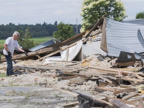 A man stands next to the remains of a barn following a tornado in St-Roch-de-l'Achigan, near Montreal, Friday, July 12, 2019.