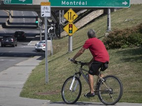 A cyclist uses the sidewalk as he makes his way north on St-Charles Blvd. near the Highway 20 overpass in Beaconsfield.