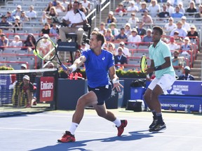 Vasek Pospisil attempts to hit a return ball while teammate Félix Auger-Aliassime looks on in their doubles match against Jeremy Chardy and Fabrice Martin of France during day 4 of the Rogers Cup at IGA Stadium in Montreal on on Monday, Aug. 5, 2019.