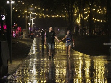 People walk in the rain on Day 1 of the ÎleSoniq electronic music festival at Parc Jean-Drapeau in Montreal on Friday, August 9, 2019.