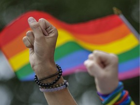 People raise their fists as they take part in a moment of silence during the Montreal Pride Parade through Rene-Levesque boulevard in downtown Montreal.