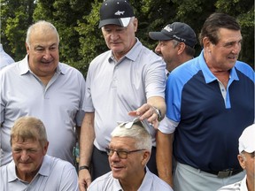 Former Montreal Canadien Larry Robinson places a golf glove on former team-mate Rejean Houle's head while having photos taken with Guy Lapointe, left, Pierre Mondou, bottom left, and Serge Savard at Savard's annual golf tournament at Islesmere Golf Club in Laval on Aug. 19, 2019.