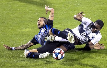 Doneil Henry, right, of the Vancouver Whitecaps takes down Montreal Impact forward Maximiliano Urruti during their MLS match at Stade Saputo on Aug. 28, 2019.