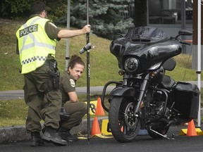 Sûreté du Québec officers examine the motorcycle driven by a homicide victim on Lionel-Daunais St. in Bourcherville Aug. 30, 2019.