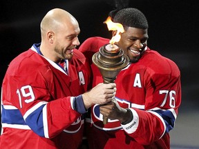Andrei Markov takes the torch from P.K. Subban during ceremony before the Canadiens’ NHL home opener against the Boston Bruins at the Bell Centre in Montreal on Oct. 16, 2014.