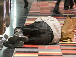 An unidentified man sleeps beside garbage cans inside the Guy Concordia métro station in downtown Montreal, Wednesday December 7, 2016.