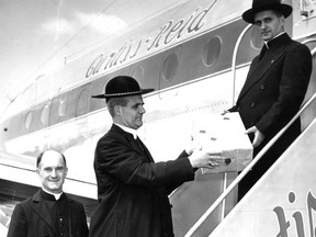 Archbishop Paul-Émile Léger, centre (he became a cardinal later), hands a box containing  relics of Marguerite Bourgeoys to Msgr. Adrien Cadotte on Aug. 21, 1950. At left is Rev. Moise Roy, also there to see off the remains as well 50 pilgrims undertaking a Holy Year journey to Rome on a Curtiss-Reid flight. Sending the remains was part of the beatification process.