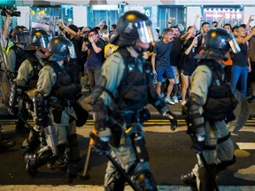 Locals shout at riot police as they chase anti-government protesters down Nathan Road in Mong Kok in Hong Kong Aug. 17.