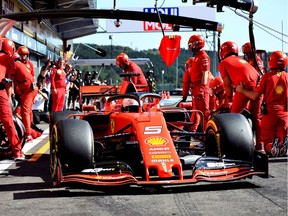 Pit crew members work on Sebastian Vettel's Ferrari during Friday practice at Spa-Francorchamps circuit.