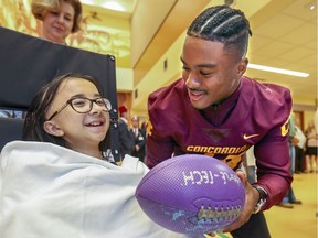 Concordia Stingers running back Kevin Foster gets a smile out of Shriners Hospital patient Tara Lam during activities at the hospital in Montreal Wednesday September 4, 2019 leading up to this weekend's Shrine Bowl football game at Concordia University versus the Laval Rouge et Or.