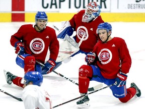 Ryan Poehling, left, goalie Cayden Primeau and Nick Suzuki follow Jake Evans's lead during stretching at Canadiens rookie camp workout at the Bell Sports Complex in Brossard.