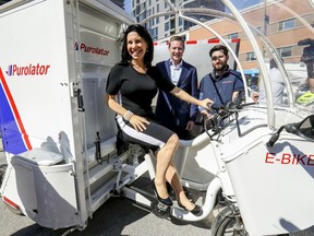 Mayor Valérie Plante sits on a Purolator e-bike, with Purolator President and CEO John Ferguson (middle), after announcing a pilot project promoting ecological delivery vehicles in Montreal Thursday September 12, 2019.