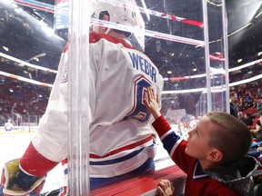 A young Canadiens fan reaches toward Shea Weber during pre-game warmup at the Bell Centre in Montreal before game against the Carolina Hurricanes on Dec. 13, 2018.