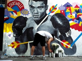 A man places a candle under a mural of the later boxer Muhammad Ali, who died in 2016 after a long battle with Parkinson's disease.