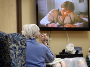 A elderly woman eats in front of a television at a Quebec seniors residence.