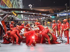 Ferrari crew members work on Sebastian Vettel's car during Friday practice for the Singapore Grand Prix.