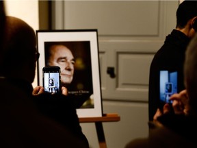 People take pictures of the portrait of former French president Jacques Chirac during a memorial ceremony at the St-Louis-des-Invalides cathedral at the Invalides memorial complex in central Paris on Sunday, Sept. 29, 2019.  Chirac died on Sept. 26 at the age of 86.