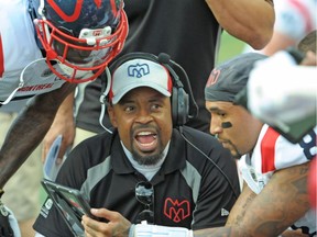 Montreal Alouettes head coach Khari Jones, centre, goes over a play with quarterback Vernon Adams Jr., right, during first half CFL football action against the Saskatchewan Roughriders in Regina on Sept. 14, 2019.