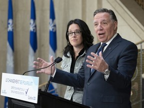 François Legault responds to reporters' questions after his government tabled a legislation to establish a new electoral system on Wednesday. Quebec Justice Minister and Minister Responsible for Democratic Institutions, Electoral Reform and Access to Information, Sonia Lebel, left, looks on.