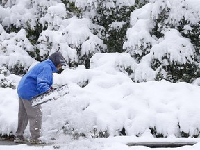 Joyce Fletcher does her best to clear the heavy snow that fell overnight in Calgary on Sunday, September 29, 2019. Darren Makowichuk/Postmedia