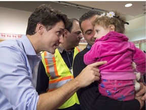 Is Justin Trudeau the refugee-supporting prime minister of 2015, or a casual racist? He is seen here greeting 16-month-old Madeleine Jamkossian, right, and her father Kevork Jamkossian, refugees fleeing the Syrian civil war.