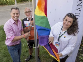 Peter Schiefke left, Yvan Cardinal middle, mayor of Pincourt and Julie Lemieux, the first known transgender person to be elected as a mayor in Canada, from the small Quebec village of Tres-Saint-Redempteur raise the gay pride flag at the office of Schiefke, in Vaudreuil-Dorion on Aug. 19, 2018.