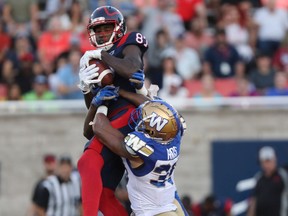 Montreal Alouettes' Eugene Lewis catches ball as he leaps above Winnipeg Blue Bombers' Marcus Rios during second half in Montreal on Sept. 21, 2019.