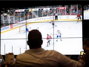 Sports fans watch the Montreal Canadiens play the Chicago Blackhawks at the Bell Centre location of Cage aux Sports in Montreal on Oct. 1, 2014.