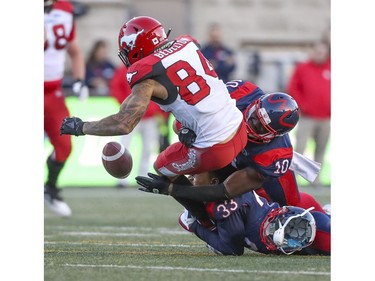 Alouettes' Jarnor Jones loses his helmet as he teams up with teammate Hénoc Muamba to cause Calgary Stampeders Reggie Begelton to fumble the football during in Montreal on Saturday, Oct. 5, 2019.