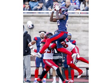 Alouettes' Eugene Lewis jumps to catch a pass over Calgary Stampeders defenders Tre Roberson and Brandon Smith in Montreal on Saturday, Oct. 5, 2019.