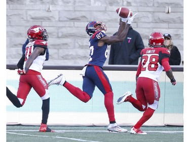 Alouettes' Eugene Lewis drops a pass between Calgary Stampeders defenders Tre Roberson and Brandon Smith in Montreal on Saturday, Oct. 5, 2019.