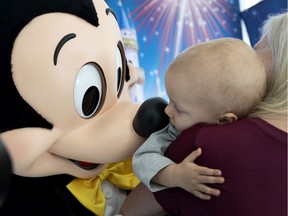 A hospital staff member holds 1 year old Louis Thiffault so he can press noses with Mickey Mouse at the Sainte-Justine Hospital in Montreal, on Thursday, October 10, 2019.