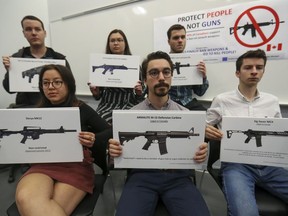 Students from engineering schools in Quebec hold signs showing legal assault-style guns during a news conference at École Polytechnique.