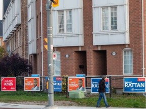 People walk past election signs for candidates on October 21, 2019 in Toronto.