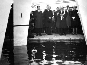 Premier Jean Lesage (front, with hands clasped) and Chomedey Mayor Jean Noël Lavoie (left) listen as a priest speaks at a ceremony on Oct. 15, 1961 inaugurating the Tripedium, a three-legged spire symbolizing the fusion the previous spring of three municipalities into the city of Chomedey. The photo is taken through the Tripedium's legs. This photo was published in the Montreal Gazette the following day.