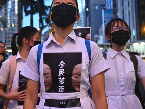 High school students chant slogans as they stick posters reading "all people masked" on their uniforms as protesters gather in the heart of Hong Kong's commercial district Central on October 4, 2019, after the government announced a ban on facemasks.
