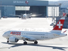 An Airbus A220 jet and a Boeing 777-300ER jet of Swiss Airlines are seen in front of a hall of SR Technics aircraft service provider at Zurich airport in Zurich, Switzerland October 16, 2019.  REUTERS/Arnd Wiegmann