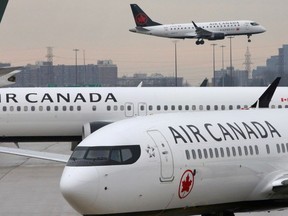 FILE PHOTO: FILE PHOTO: Two Air Canada Boeing 737 MAX 8 aircrafts are seen on the ground as Air Canada Embraer aircraft flies in the background at Toronto Pearson International Airport in Toronto, Ontario, Canada, March 13, 2019. REUTERS/Chris Helgren/File Photo/File Photo
