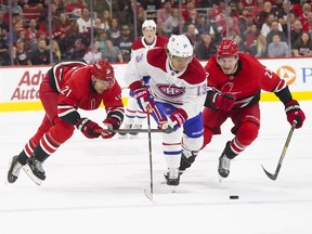 Montreal Canadiens centre Max Domi tries to carry the puck past Carolina Hurricanes defenceman Brett Pesce (22) and right-wing Nino Niederreiter (21) during the first period at PNC Arena in Raleigh, N.C., on Oct. 3, 2019.