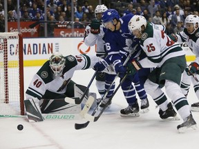 Toronto Maple Leafs forward Mitch Marner (16) battles with Minnesota Wild defenceman Jonas Brodin (25) and goaltender Devan Dubnyk for a rebound during the first period at Scotiabank Arena in Toronto on Oct. 15, 2019.