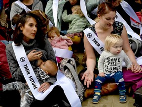 Mothers hold their babies as they protest about the climate crisis outside Google offices during the tenth day of demonstrations by the climate change action group Extinction Rebellion, in London, on Oct. 16, 2019.